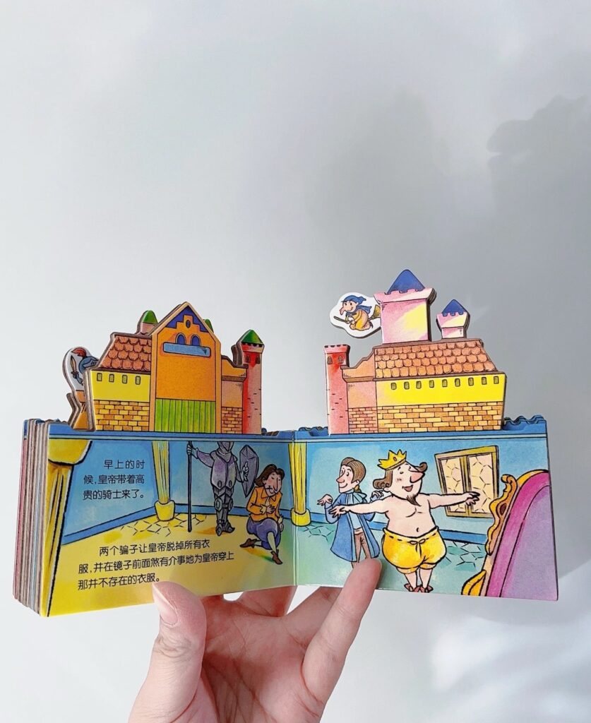 The Emperor's New Clothes: Custom-Shaped Thickened Board Book Open hardcover custom-shaped book showing The Emperor's New Clothes story with 3D castle pop-up inner pages.